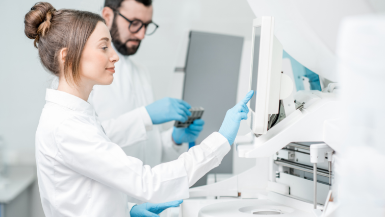 Dwóch laborantów: kobieta i mężczyzna dokonują badań w czystym laboratorium.