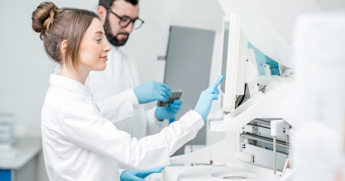 Dwóch laborantów: kobieta i mężczyzna dokonują badań w czystym laboratorium.